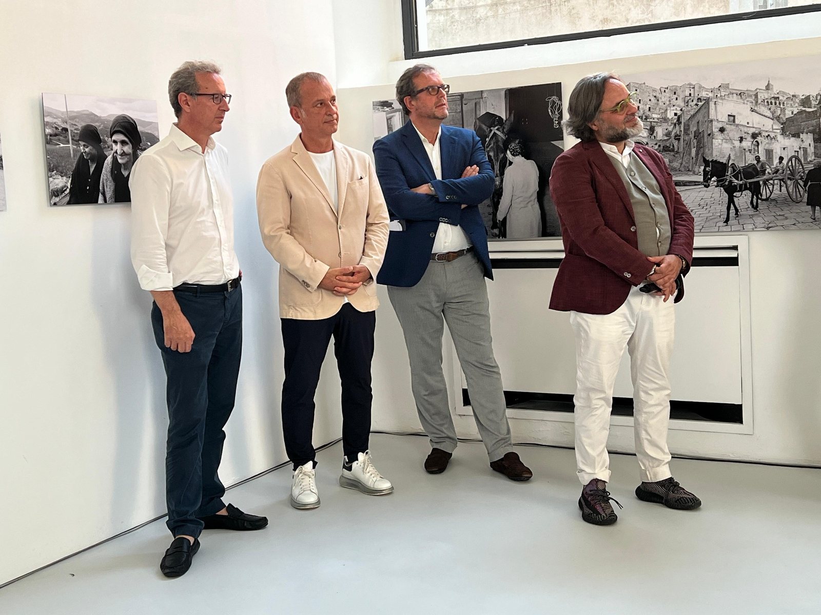 Quattro persone in una galleria davanti a opere fotografiche